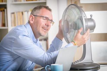 Obraz premium Man suffers from heat in the office or at home
