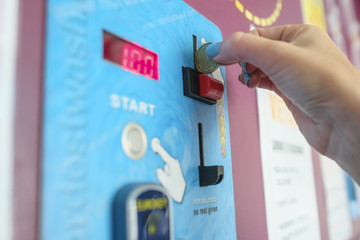 hand that lowers a coin into a machine close-up