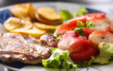 carne de cerdo con papas criollas, ensalada de lechuga, tomate y fresa