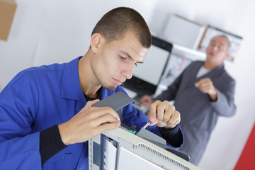 young man fixing a printing machine