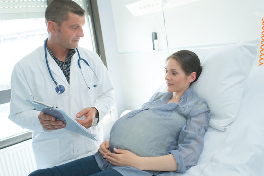 male gynecologist showing ultrasound photo to pregnant woman