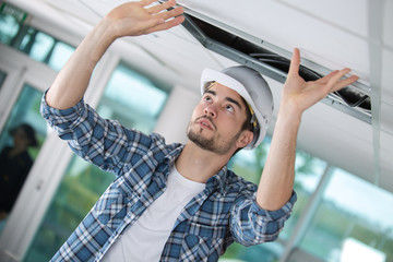 worker putting back the ceiling plaster board cover