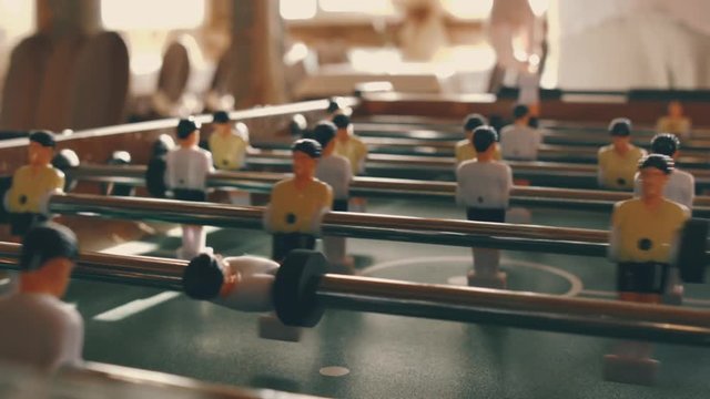 People playing in table football or kicker with miniature players. Table football game with yellow and white players. Employees playing table soccer indoor-game in the office during break time.
