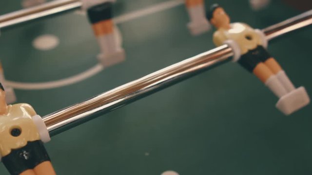 People playing in table football or kicker with miniature players. Table football game with yellow and white players. Employees playing table soccer indoor-game in the office during break time.