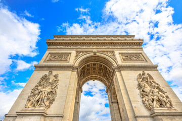 Bottom view of Arch of Triumph at center of Place Charles de Gaulle with clouds and blue sky. Popular landmark and famous tourist attraction in Paris capital of France in Europe. - obrazy, fototapety, plakaty