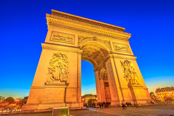 Fototapeta na wymiar Night view of Arch of Triumph at the center of the Place Charles de Gaulle. Bottom view of popular landmark at blue hour and famous tourist attraction in Paris capital of France in Europe.