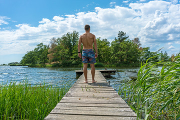 Sexy young man on a jetty in a beautiful coastal landscape  © DZiegler