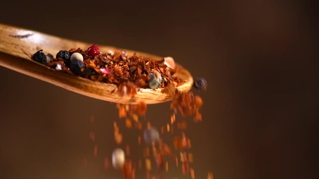 Spices falling from wooden spoon. Pepper, paprika, seasonings closeup. Cooking. Various Indian spices and herbs on wooden table. Slow motion. 3840X2160 4K UHD video footage
