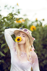 Beautiful woman in a rural field scene outdoors, with sunflower and sunhat, lust for life, summerly, autumn mood