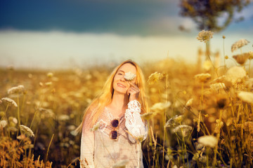 Beautiful woman in a flower meadow with sunglasses and flower, lust for life, summerly, autumn mood 