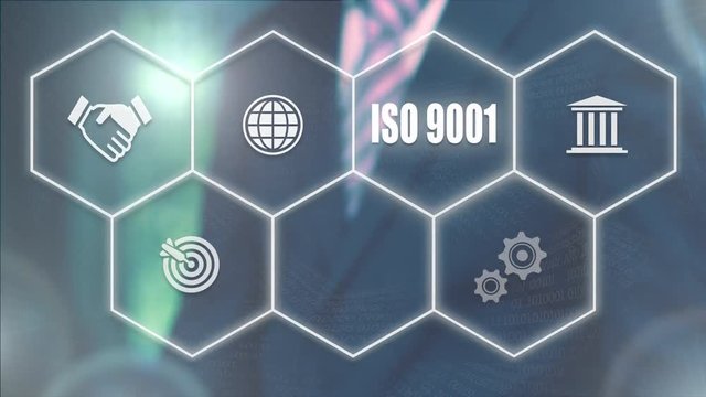 A businessman's hand selecting a ISO 9001 concept button on a futuristic computer screen.