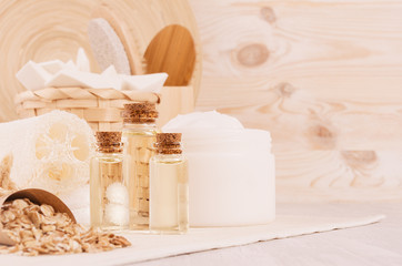 Organic homemade white cosmetics, bottles with oil and raw oatmeal flakes, bath accessories on light beige wooden background, border.