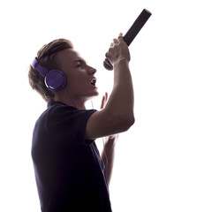 silhouette of young man in headphones singing into microphone on white isolated background