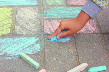 The child paints with chalk on the asphalt.