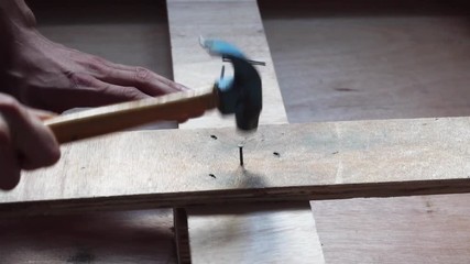 Hammering nail into wooden plank