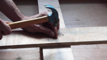 Hammering nail into wooden board in slow motion