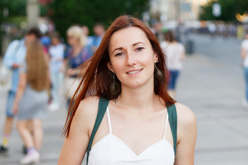 Pretty young smiling woman going down a street