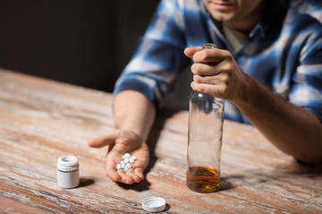 depression, drug abuse and addiction people concept - unhappy drunk man with bottle of alcohol and...