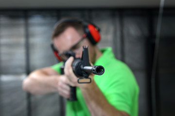 Fototapeta na wymiar Mężczyzna strzela z karabinu. Przystojny mężczyzna trenuje strzelanie na strzelnicy sportowej.