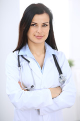 Brunette female doctor standing straight at hospital. Medicine and health care concept