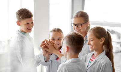 education, science and children concept - happy kids making high five at school laboratory