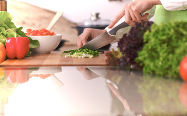 Close Up of human hands cooking vegetable salad in kitchen on the glass table with reflection. Healthy meal, and vegetarian food concept