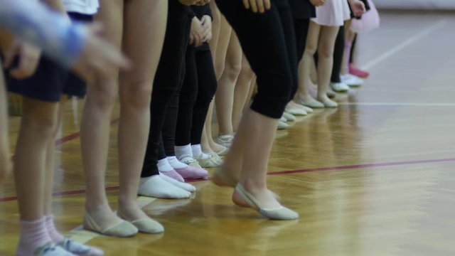 Children gym class for girls - a group engaged in dance gymnastics - legs row