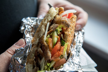 Mann isst Döner im Fladenbrot mit Salat und Kalb Fleisch in Aluminiumfolie 