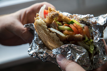 Mann isst Döner im Fladenbrot mit Salat und Kalb Fleisch in Aluminiumfolie 