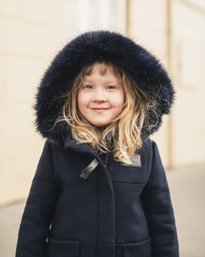 Portrait of smiling girl wearing fur coat while standing outdoors