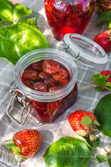 Strawberry jam and juicy ripe strawberries on a wooden table in the garden on a summer sunny afternoon in a rustic style, the concept of gardening, healthy organic vitamin nutrition