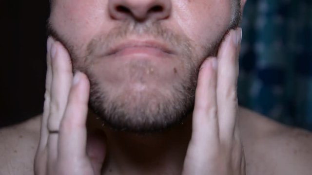 Man check and shaves his face. Man shaving with soap and manual razer. Close up of man shaving beard.