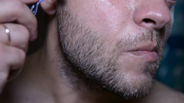 Man check and shaves his face. Man shaving with soap and manual razer. Close up of man shaving beard.