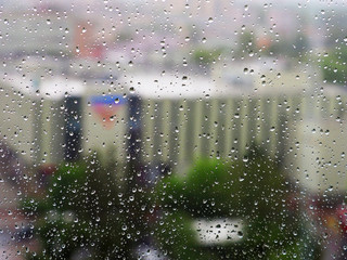 View of the city behind the glass. Glass with drops of water from the rain. The city is a top view