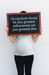 Pregnant woman holds board with quote