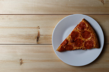a slice of pepperoni pizza on a wooden table. Top view. Copy space and text area.