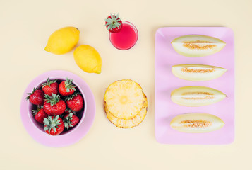 Fresh strawberries in bowl and melon on pastel yellow background.