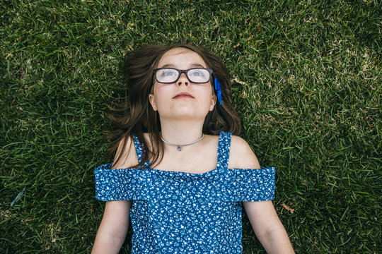 Overhead view of thoughtful girl lying on grassy field at park