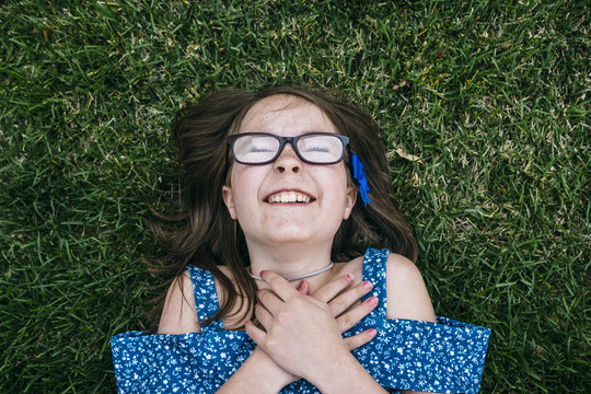Overhead view of cheerful girl lying on grassy field at park
