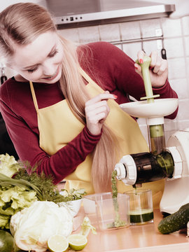 Woman in kitchen making vegetable smoothie juice