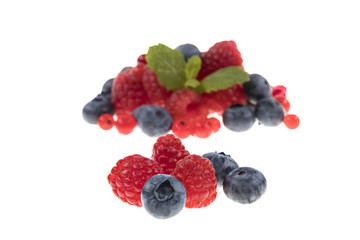 Drei Himbeeren und drei Heidelbeeren auf weissem Hintergrund