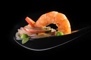 A closeup of spoon food featuring tasty shrimp on layers of glass noodles