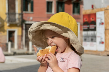 Little girl eating a pice of bread in Venice Italy 