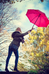 Woman walking in park with umbrella, strong wind