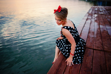 A beautiful young woman dressed sitting on the pier