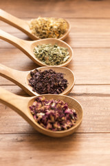 Wooden spoons with different herbs for infusion.