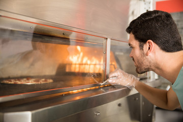 Chef looking at pizza baking in modern oven