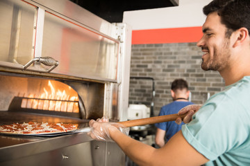Chef baking pizza bread in oven at commercial kitchen