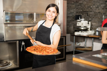 Glimlachende chef-kok die grote schop met pizza houdt