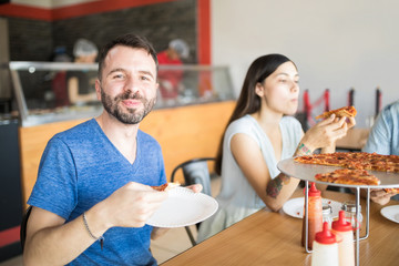 Smiling man with beard enjoying pizza